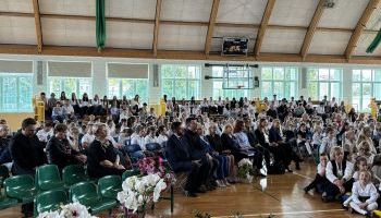 hala sportowa w szkole, zebrani uczniowie i kadra pedagogiczna, wręczanie kwiatów przez burmistrza