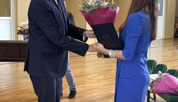 hala sportowa w szkole, zebrani uczniowie i kadra pedagogiczna, wręczanie kwiatów przez burmistrza
