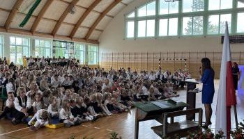 hala sportowa w szkole, zebrani uczniowie i kadra pedagogiczna, wręczanie kwiatów przez burmistrza