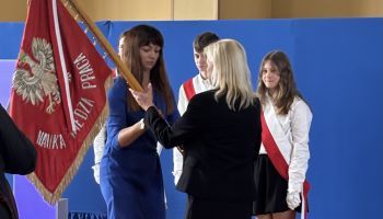 hala sportowa w szkole, zebrani uczniowie i kadra pedagogiczna, wręczanie kwiatów przez burmistrza