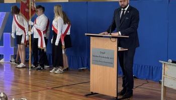 hala sportowa w szkole, zebrani uczniowie i kadra pedagogiczna, wręczanie kwiatów przez burmistrza