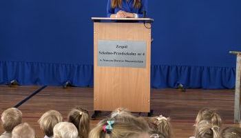 hala sportowa w szkole, zebrani uczniowie i kadra pedagogiczna, wręczanie kwiatów przez burmistrza