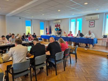 sala konferencyjna, stół na podwyższeniu, osoby siedzące,