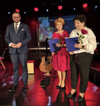 wręczanie nagród dla wyróżnionych nauczycieli, dwie kobiety z różami obok stoi Burmistrz