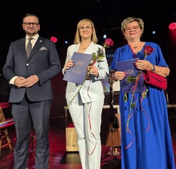 wręczanie nagród dla wyróżnionych nauczycieli, dwie kobiety z różami, obok Burmistrz