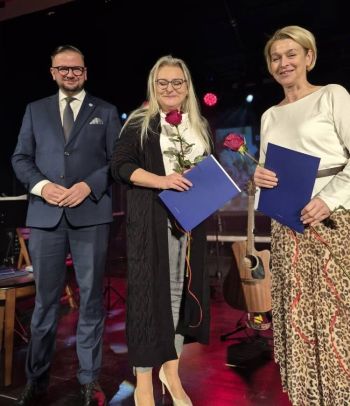 wręczanie nagród dla wyróżnionych nauczycieli, dwie kobiety z różami, obok Burmistrz