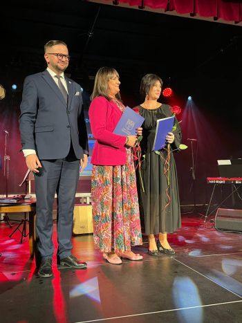 wręczanie nagród dla wyróżnionych nauczycieli, dwie kobiety z różami, obok Burmistrz