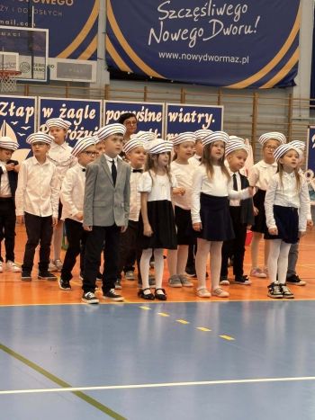 hala sportowa, dzieci ubrane na galowo, zaproszeni goście, występy z biało czerwonymi flagami