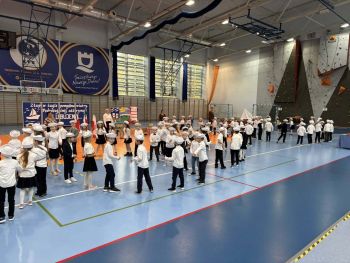 hala sportowa, dzieci ubrane na galowo, zaproszeni goście, występy z biało czerwonymi flagami