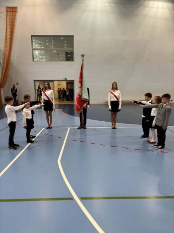 hala sportowa, dzieci ubrane na galowo, zaproszeni goście, występy z biało czerwonymi flagami