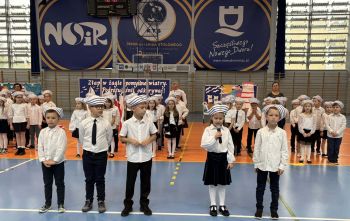 hala sportowa, dzieci ubrane na galowo, zaproszeni goście, występy z biało czerwonymi flagami