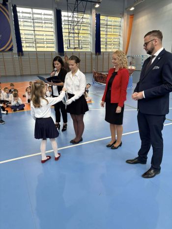 hala sportowa, dzieci ubrane na galowo, zaproszeni goście, występy z biało czerwonymi flagami