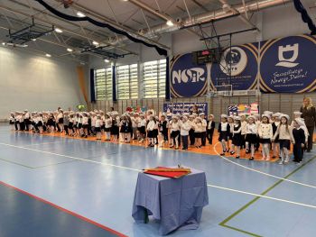 hala sportowa, dzieci ubrane na galowo, zaproszeni goście, występy z biało czerwonymi flagami
