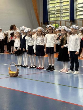 hala sportowa, dzieci ubrane na galowo, zaproszeni goście, występy z biało czerwonymi flagami