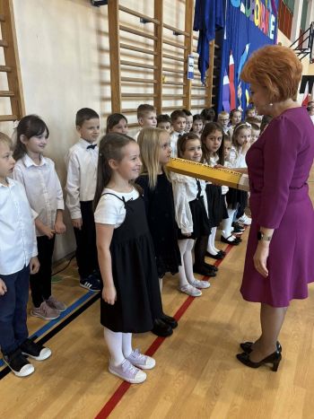sala gimnastyczna, dzieci ubrane na galowo, dekoracja ślubowania, zaproszeni goście