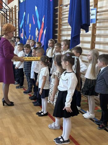 sala gimnastyczna, dzieci ubrane na galowo, dekoracja ślubowania, zaproszeni goście