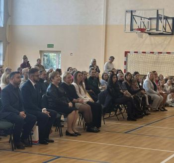 sala gimnastyczna, dzieci ubrane na galowo, dekoracja ślubowania, zaproszeni goście