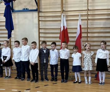 sala gimnastyczna, dzieci ubrane na galowo, dekoracja ślubowania, zaproszeni goście