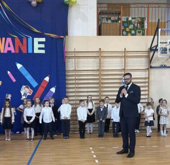 sala gimnastyczna, dzieci ubrane na galowo, dekoracja ślubowania, zaproszeni goście