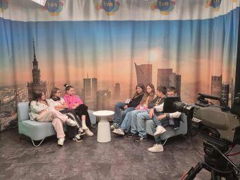 dwie kanapy na których siedzi młodzież, pozorowane studio, po prawej kamera