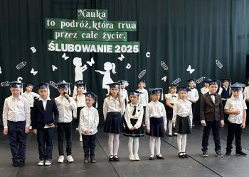 sala gimnastyczna, dzieci ubrane na galowo, dekoracja ślubowania, zaproszeni goście