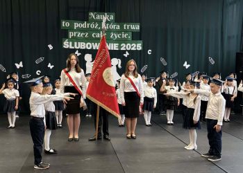 sala gimnastyczna, dzieci ubrane na galowo, dekoracja ślubowania, zaproszeni goście