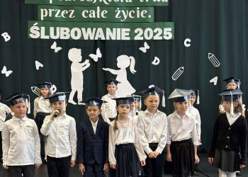 sala gimnastyczna, dzieci ubrane na galowo, dekoracja ślubowania, zaproszeni goście