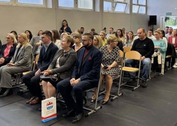 sala gimnastyczna, dzieci ubrane na galowo, dekoracja ślubowania, zaproszeni goście