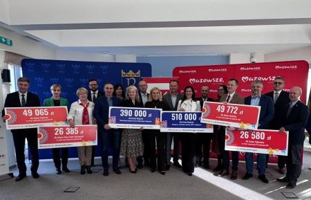 wspólne zdjęcie osób trzymających pamiątkowe bony z kwotami dofinansowania