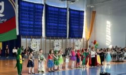 dzieci w kolorowych strojach, występy dzieci, hala sportowa, zaproszeni goście na trybunach