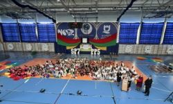 dzieci w kolorowych strojach, występy dzieci, hala sportowa, zaproszeni goście na trybunach