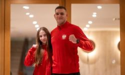 zawodniczka i trener ubrani w czerwone bluzy, oboje trzymają ściśnięte dłonie w geście walki