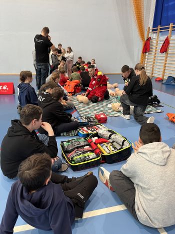 Hala sportowa, dzieci zebrane na hali, zajęcia sportowe oraz z udzielania pierwszej pomocy