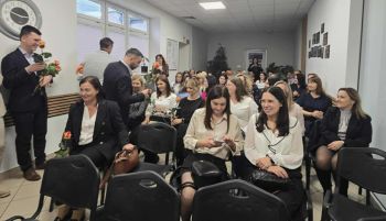 sala konferencyjna, na krzesłach siedzą zaproszeni pracownicy społeczni, rozdawanie kwiatów, zdjęcie wspólne