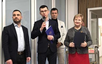 sala konferencyjna, na krzesłach siedzą zaproszeni pracownicy społeczni, rozdawanie kwiatów, zdjęcie wspólne