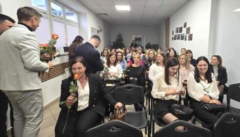 sala konferencyjna, na krzesłach siedzą zaproszeni pracownicy społeczni, rozdawanie kwiatów, zdjęcie wspólne
