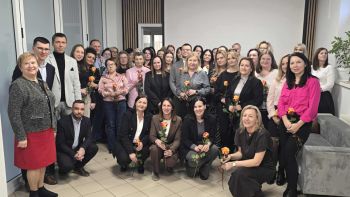 sala konferencyjna, na krzesłach siedzą zaproszeni pracownicy społeczni, rozdawanie kwiatów, zdjęcie wspólne