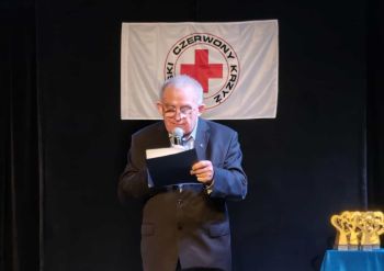 prezes zarządu pck stoi na scenie, czyta z kartki