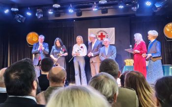 wyróżnione osoby na scenie, kobiety trzymają w rękach czerwone róże