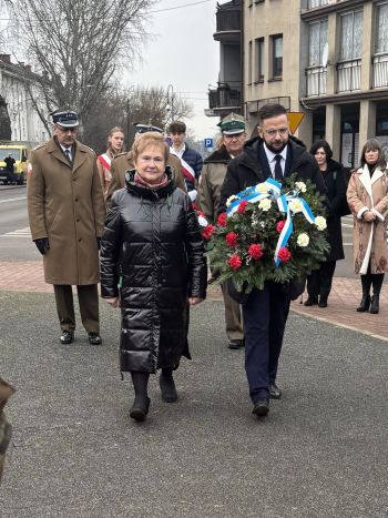 uroczystość pod pomnikiem, przemówienia, składanie kwiatów, poczty sztandarowe ze szkół