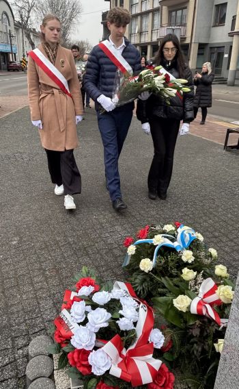 uroczystość pod pomnikiem, przemówienia, składanie kwiatów, poczty sztandarowe ze szkół