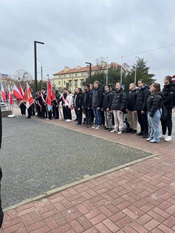 uroczystość pod pomnikiem, przemówienia, składanie kwiatów, poczty sztandarowe ze szkół