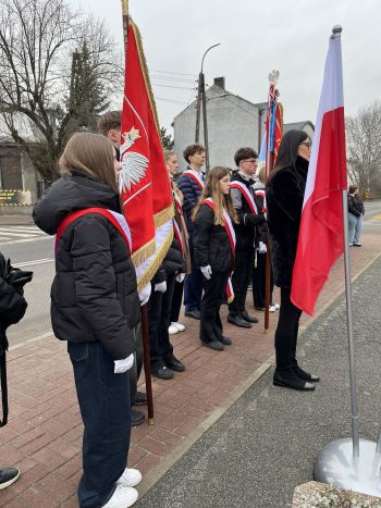 uroczystość pod pomnikiem, przemówienia, składanie kwiatów, poczty sztandarowe ze szkół