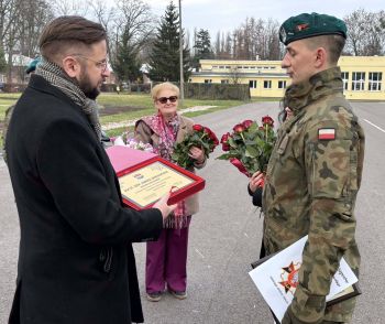 plac, żołnierze stojący na baczność, gratulacje dla bohatera, wręczanie kwiatów i pamiątkowej tabliczki
