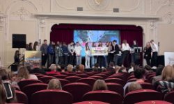 sala kinowa, zebrana młodzież, wręczanie nagród na scenie, prezentacja wyświetlana na ekranie