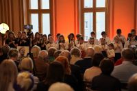 Dziewczynki i chłopcy stojąc grają na fletach.