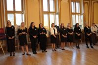 Dziesięć kobiet stojących na parkiecie w sali.