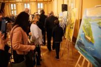 Osoby oglądające obrazy na sztalugach.