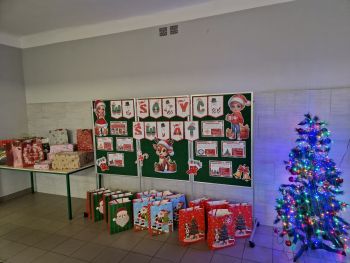 tablica z napisem wesołych świąt, pod tablicą torby prezentowe