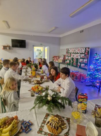 dzieci ubrane odświętnie siedzą przy stole wigilijnym